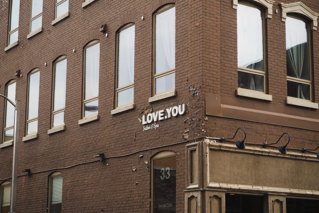 Vintage high-rise brown brick building with symmetrical arched windows and the words "love.you" lettered in white on the corner of the building.