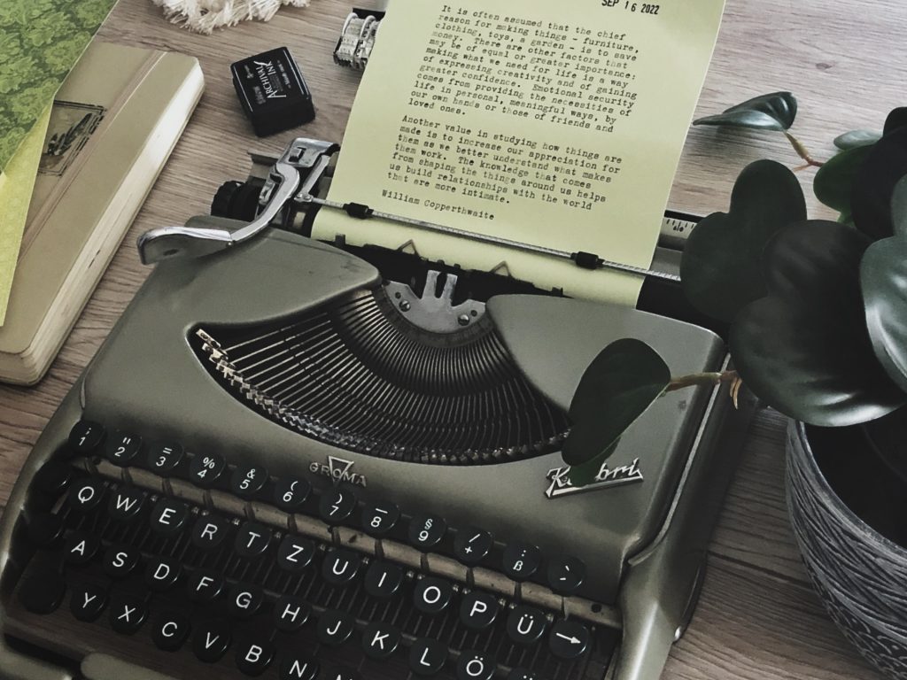 Typewritings 12: Why we make things. Light green paper with a typewritten quote is shown on a vintage typewriter. The text of the quote is contained within the post. Also on the desk, a green notebook and other green papers.